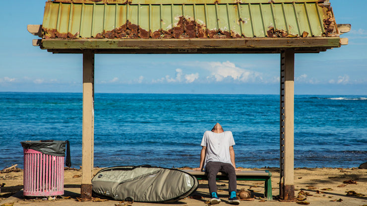 Cam Richards sits on a bench next to the smuggler surfboard travel bag.
