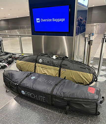 Two surfboard travel bags labeled 'Pro-Lite' at an airport baggage claim area.