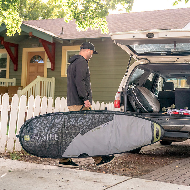 Surfer carry's rhino surf travel bag to car. surfboard bag, surfboard travel bags