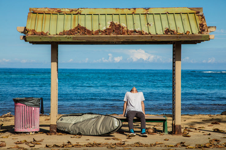 Cam Richards sits on a bench next to the smuggler surfboard travel bag.