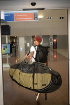 Surfer carrying Pro-Lite Finless coffin surfboard travel bag at airport.
