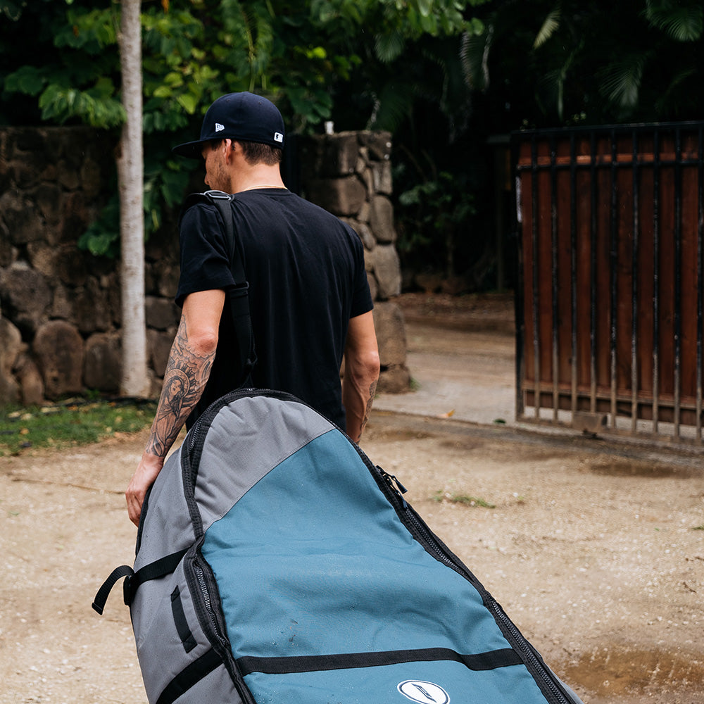 Wheeled coffin bag being pulled with shoulder strap.