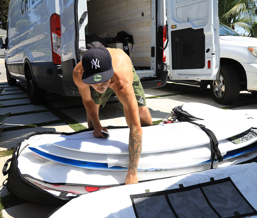 Securing surfboards in travel coffin bag with internal seatbelt straps.