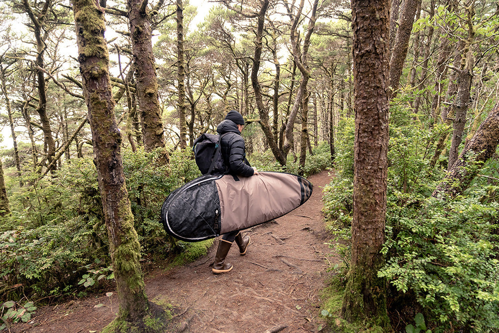 Surfer walking on trail with session fish hybrid day bag.