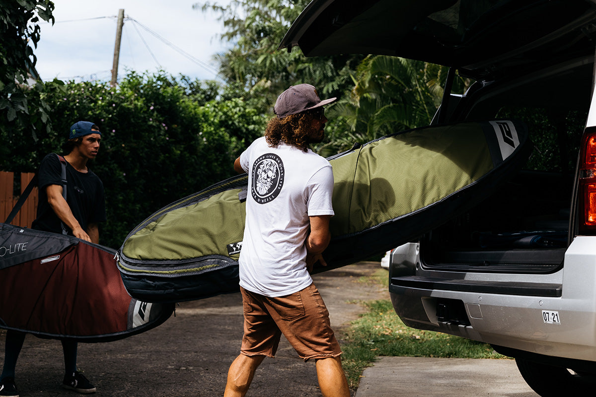 Surfer loading smuggler bag into a car.